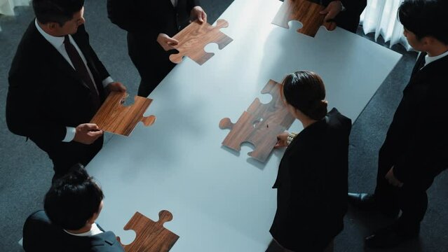 Top view of business people putting jigsaw together at meeting room. Professional marketing team standing at table while gathering puzzle piece. Show unity, cooperation and team working. Directorate.