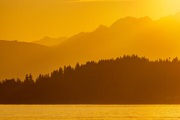 A setting sun casts a golden glow over the Olympic mountains and Puget Sound