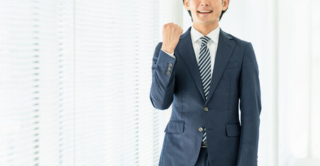 オフィスでガッツポーズする若いアジア人男性ビジネスマン
