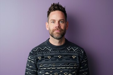 Portrait of a handsome young man with beard and mustache wearing sweater against purple background - obrazy, fototapety, plakaty