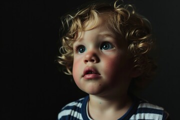 Portrait of a cute little boy with blond curly hair and blue eyes