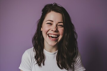 Portrait of a beautiful young woman laughing on a purple background.