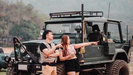 Man and woman engage in exploration, the woman pointing into the distance, with a vintage off road car in the foreground.