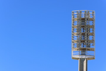 Light-emitting diode (LED) light tower, or floodlights, at large sports stadium or venue.  Clear blue sky background.  Copy space to left.