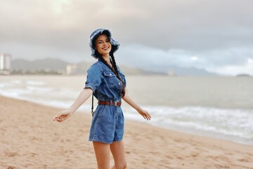 Beautiful young woman enjoying a summer vacation on a tropical beach, surrounded by the stunning nature of the ocean and sky. She is an attractive lady, with long, flowing hair, wearing a stylish