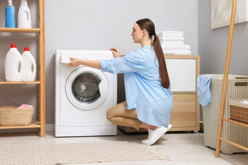 Beautiful woman near washing machine in laundry room