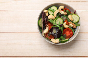 Tasty fresh vegetarian salad on light wooden table, top view. Space for text