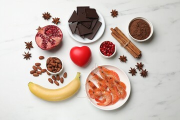 Natural aphrodisiac. Different food products and red decorative heart on white marble table, flat...