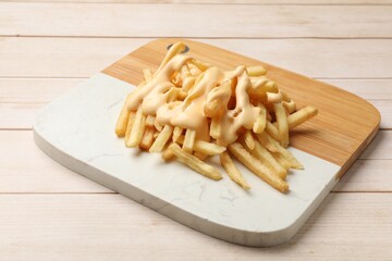 Delicious french fries with cheese sauce on wooden table