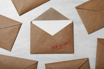 Top Secret stamp. Paper envelopes on light grey table, flat lay