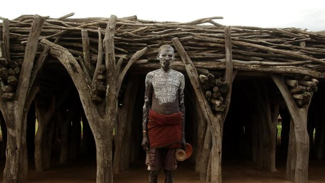 Tribe Elderly Man with Body Paint in Traditional Clothes looking at the camera
