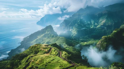 Schilderijen op glas Majestic mountain landscape with ocean view - This stunning image captures the essence of a lush green mountainous landscape overlooking the vast ocean, with clouds enveloping the peaks © Tida