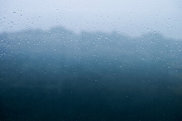 梅雨　雨の滴のついた窓ガラスの奥の山の風景　6月・梅雨明け・水滴