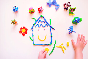 Child sculpting plasticine house like Earth planet, flower and animals. Homework for earth day....