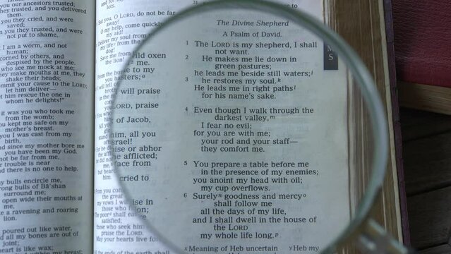 Close up view on Psalm 23 or the old testament, Holy Bible with a glass magnifier. The Lord is our shepherd, famous scripture passage.