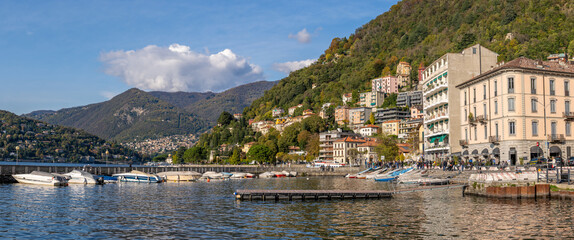 Pier and boats docked at marina on Lake Como in the harbor of the city of Como, Lombardy, Northern Italy - obrazy, fototapety, plakaty