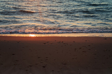 Beach sand with pebbles on the edge of the Baltic Sea at sunset, Curonian Spit, Kaliningrad region, Russia