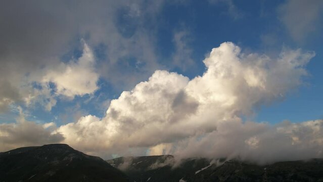Majestic cumulus clouds looming over mountains, hints of blue sky