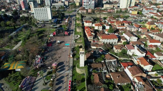 City Tower and Old Stone Castle Walls Along the Main Street of Elbasan, Embraced by Green Palms on a Sunny Spring Day