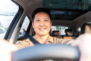 A man is driving a car and smiling.