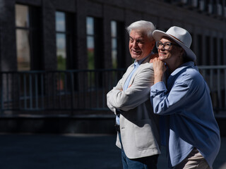 Stylish mature couple on a walk. Portrait of gray-haired man and woman hugging outdoors. 