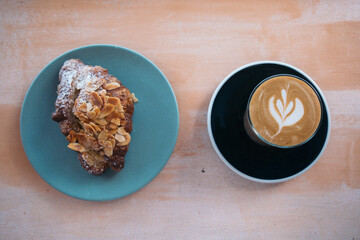 almond croissant on a blue plate and a cup of coffee for morning tea