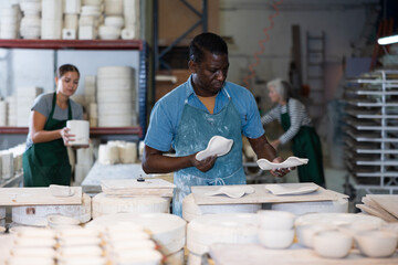 African american male artisan having ceramics in hands and standing in workshop