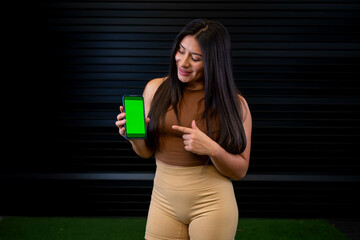 female athlete pointing at the application on her cell phone screen.