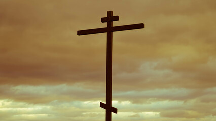 A holy wooden Christian cross against the background of gloomy clouds in the sky. The concept of faith in Jesus Christ. Easter background.