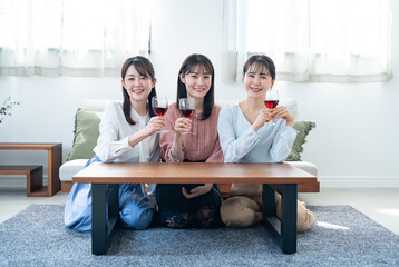 自宅で赤ワインを飲む日本人女性３人