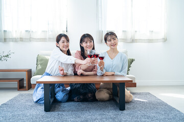 自宅で赤ワインを飲む日本人女性３人
