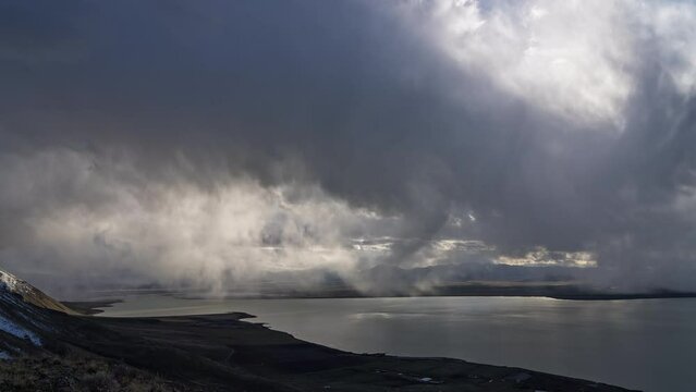 Timelapse of the sun peaking through storm moving over Utah Lake during stormy weather.