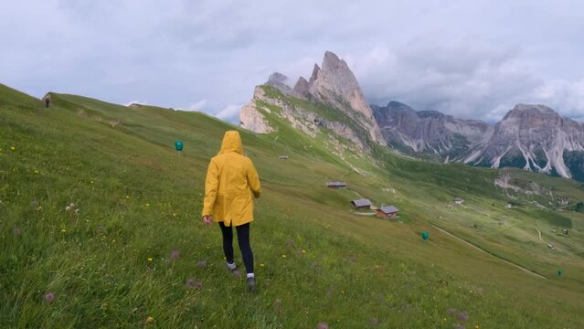 Back View Of Female Hiker In Yellow Jacket Running Towards Seceda Mountain In Italy. slow motion shot