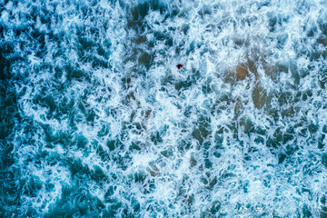 Aerial top view of ocean waves full frame and small people.