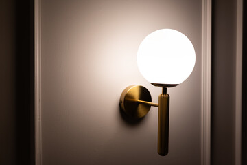 Round lamp, full moon shape with the light bulb inside shining on the wall background in the dark room with copy space.