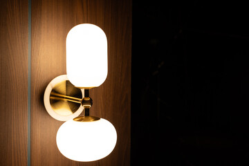Lamp with the light bulb inside shining on the wall background in the dark room with copy space.