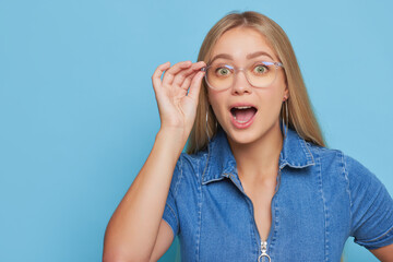 a woman wearing glasses and a blue shirt is making a surprised face