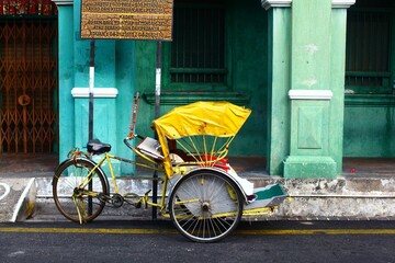 Horizontal shot of a yellow cycle rickshaw in Georgetown, Malaysia