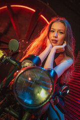 Fototapeta na wymiar Beautiful futuristic girl posing near neon motorbike in the neon lights. Cyberpunk concept.
