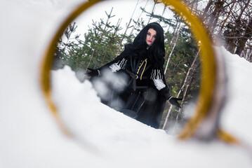 Beautiful young enchantress walking in the winter forest.