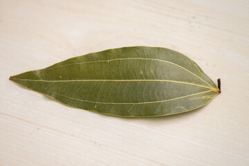 Dried bay leaf on a wooden textured surface. It is also known as Tej Pata, Cassia leaves,...