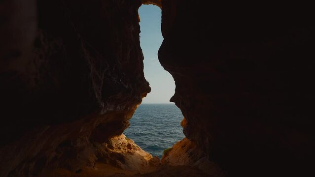 Hidden cave on Malta island. Nature seaside water waves, sky and clouds. Scenic rock formation.