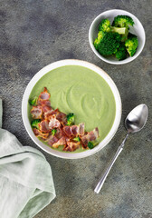 Creamy broccoli soup with bacon and croutons on a gray background. Top view