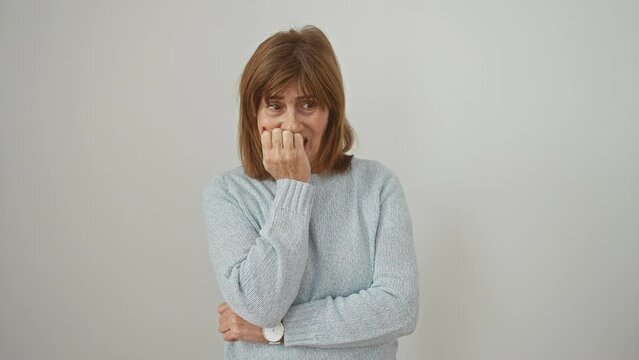 Stressed middle age woman wearing sweater bites nails, manifesting anxiety, a universal struggle. isolated on white background, the fear in her eyes undeniable.