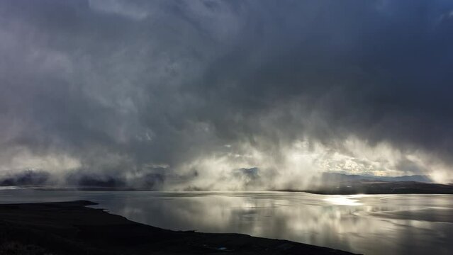 Timelapse of low clouds moving over Utah Lake during spring storm as light shines through.