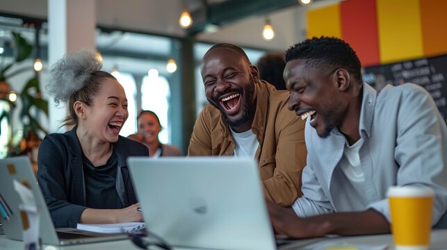 Company employees having fun laughing together around the computer