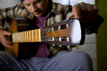 man moving headstock of an acoustic guitar, tuning