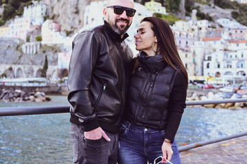  Happy smiling beautiful  Tourists  couple traveling in Italy poses and making photos near the Cathedral of Amalfi  .Family on vacation on Amalfi coast in Italy.  Italy trip concepr