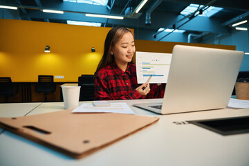 Young asian businesswoman showing business graph during video call on laptop