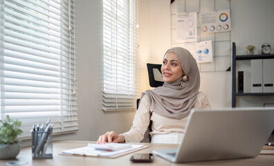 Attractive Muslim accounting business woman working using laptop in modern office